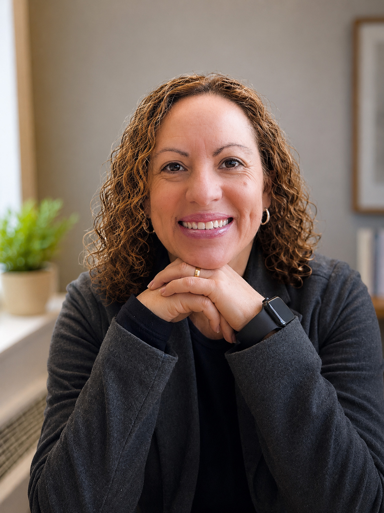 Web designer smiling at her desk in a bright creative workspace.